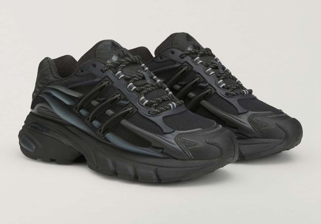 Par de Pharrell x adidas Adistar Jellyfish Triple Black en vista tres cuartos, con las tres tiras moldeadas en negro sobre la malla
