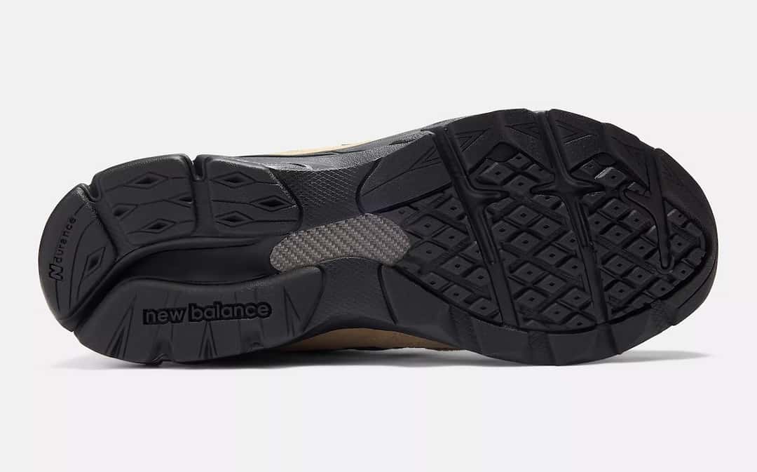 Suela negra del JJJJound x New Balance 990v3 Tan Suede vista desde abajo, con el dibujo de rombos y el logo new balance