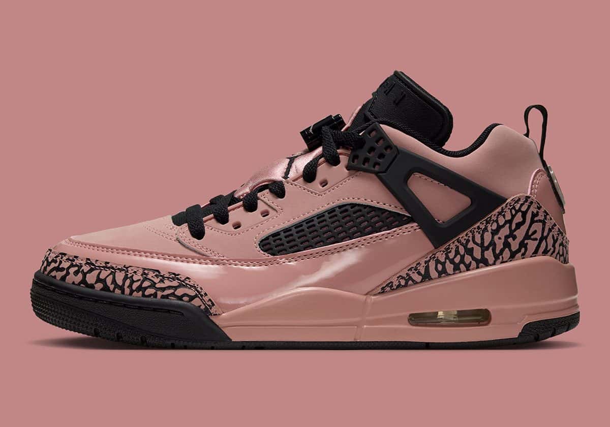 Jordan Spizike Low Rust Pink de perfil sobre fondo rosa, con charol rosa óxido, estampado cemento, las alas negras y la suela negra