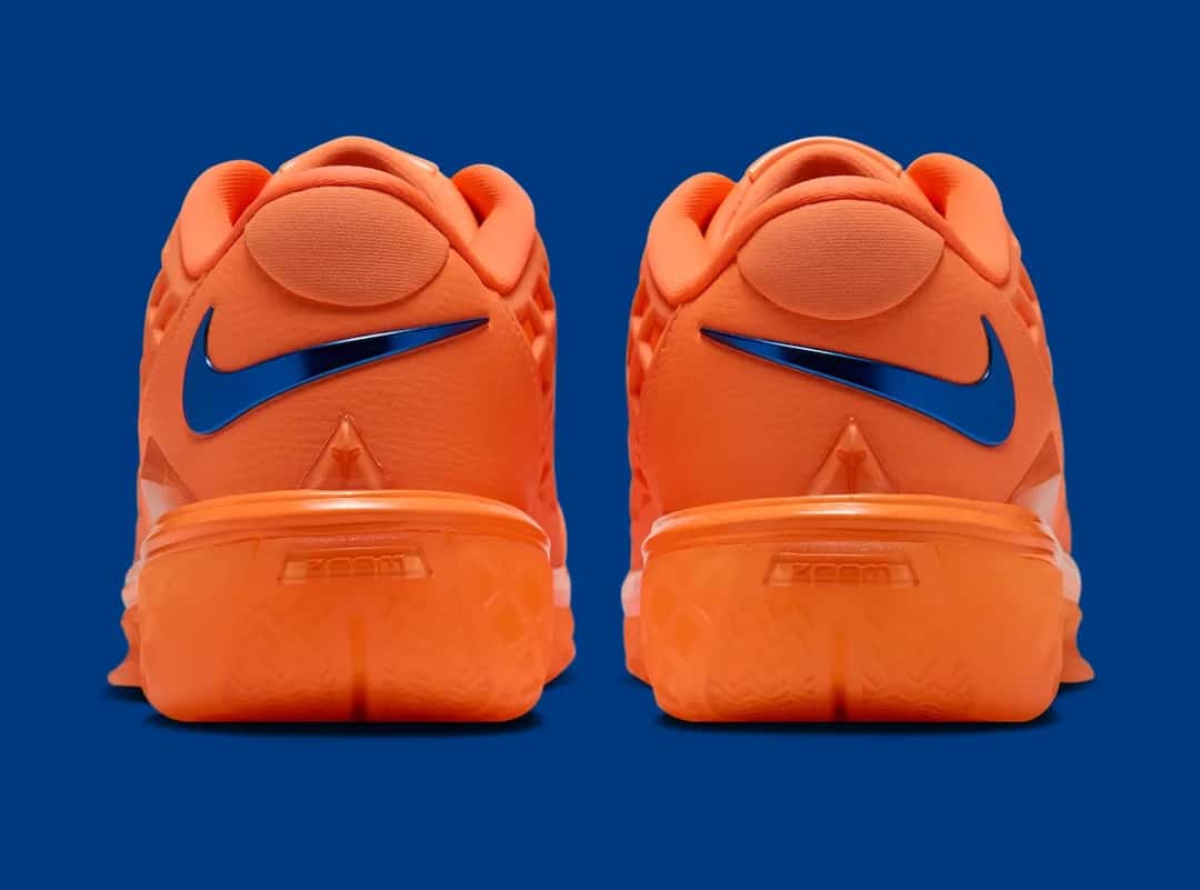 Talones de la Nike Kobe 3 Low Protro Arancia, con el Swoosh azul metalizado sobre el naranja, sobre fondo azul