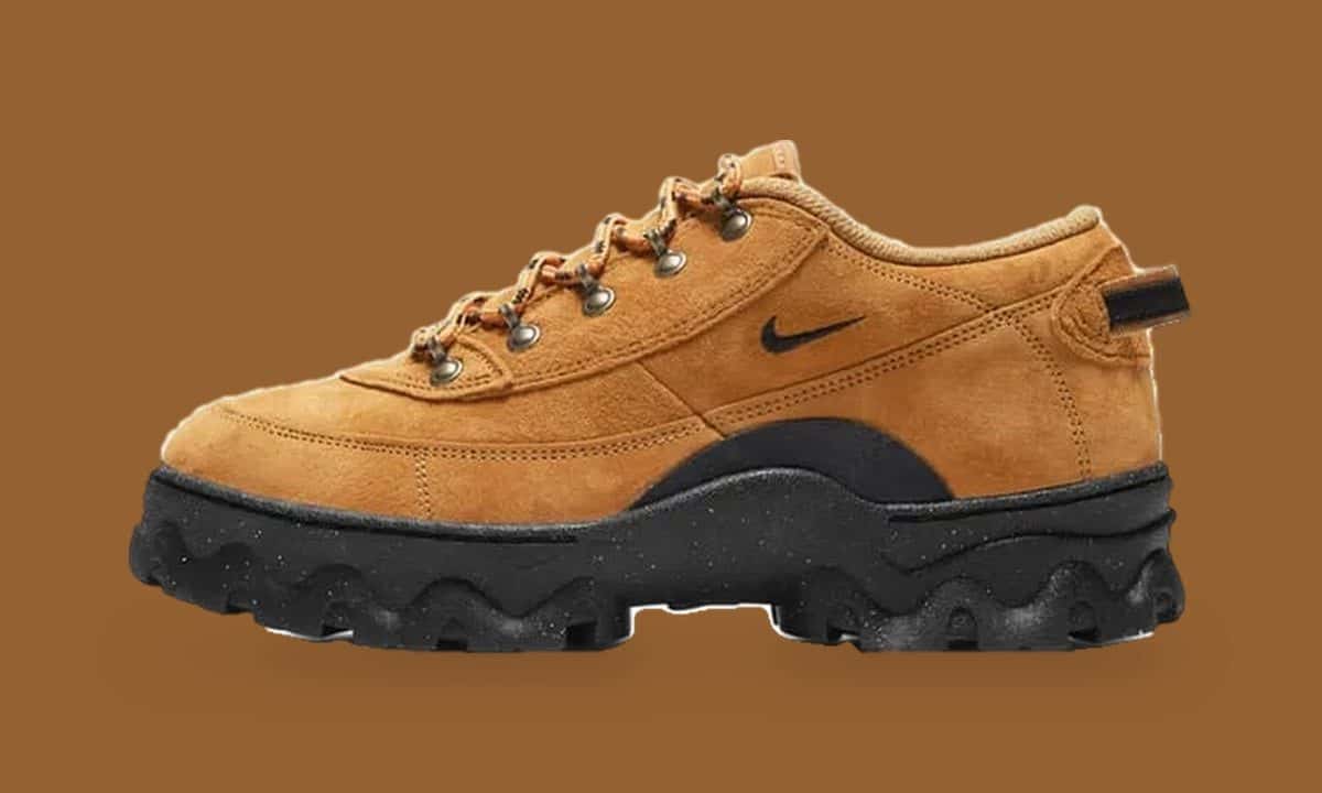 Nike Air Lahar Low color wheat de gamuza de perfil, con Swoosh negro, ojales metálicos y suela negra de taco pesado, sobre fondo marrón