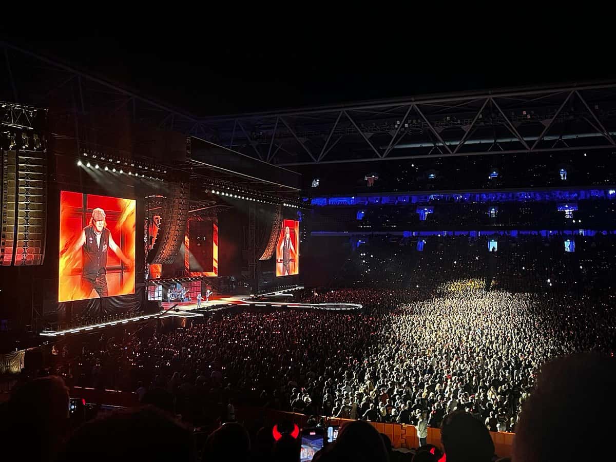 Foto de archivo de la gira Power Up de AC/DC en Brisbane, en diciembre de 2025: el escenario iluminado de azul, Brian Johnson con gorra en las pantallas gigantes y el estadio lleno de público