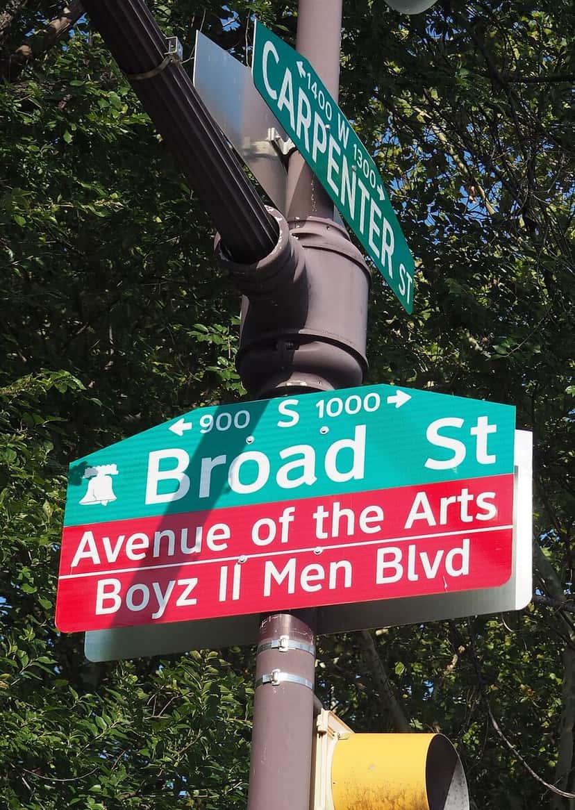 Cartel de calle en Filadelfia con los nombres Broad St, Avenue of the Arts y Boyz II Men Blvd, colgado de un poste junto a unos árboles (foto de archivo, agosto de 2017). Foto: Rgs25, CC BY-SA 4.0, vía Wikimedia Commons