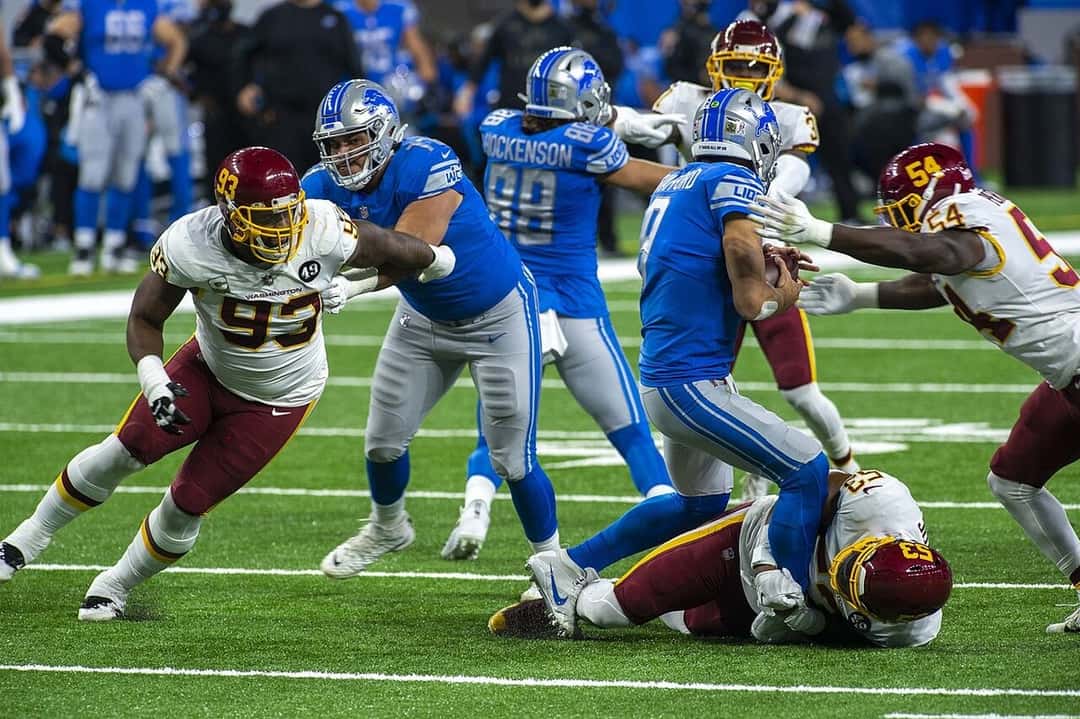 Jugadores de los Detroit Lions, de camiseta azul, y de Washington, de blanco y bordó, en una jugada en el Ford Field de Detroit (foto de archivo, noviembre de 2020). Foto: All-Pro Reels, CC BY-SA 2.0, vía Wikimedia Commons