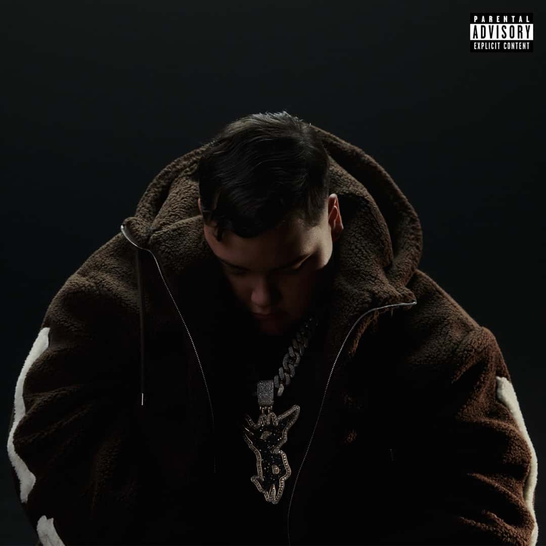 Portada de «MAN IN BLACK», el disco de FloyyMenor de 2026: el cantante, con buzo oscuro y cadena plateada, mira hacia abajo sobre un fondo negro