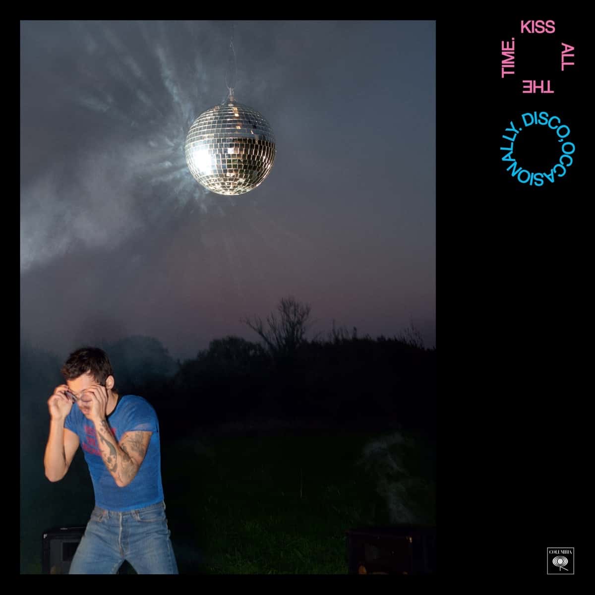 Portada de «Kiss All the Time. Disco, Occasionally», de Harry Styles: el cantante se cubre la cara en un campo al anochecer, bajo una bola de espejos que cuelga del cielo