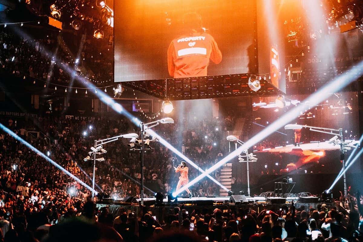 J. Cole canta en el escenario de un estadio cubierto lleno de gente, entre haces de luz blanca y una pantalla gigante, en julio de 2017 (foto de archivo)