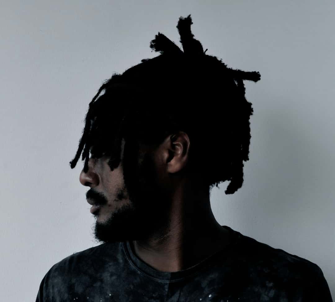 Foto de archivo: retrato de prensa de k-os de 2011, de perfil, con rastas y remera oscura frente a una pared gris. Foto: Nettwerk Artist Management (Monika Selnar), CC BY-SA 3.0, vía Wikimedia Commons