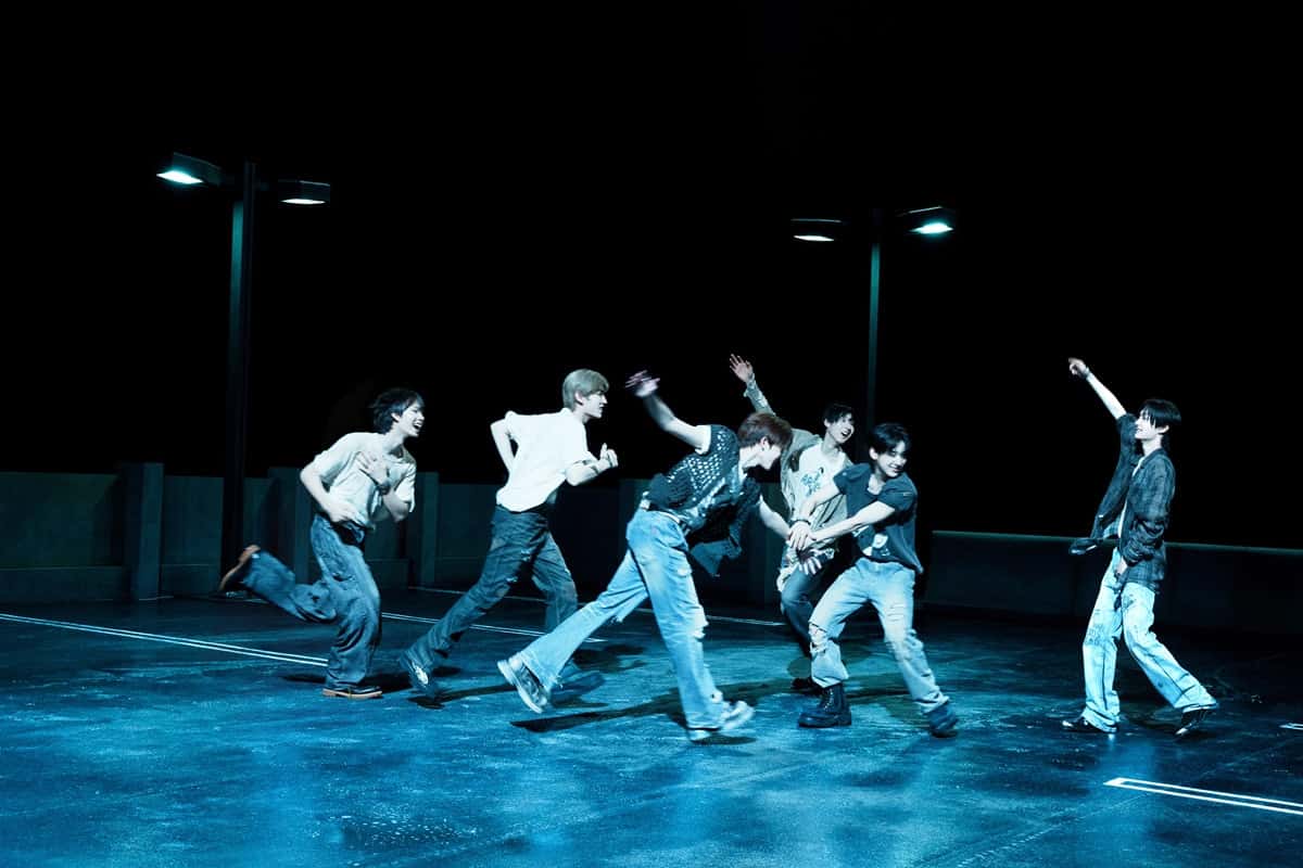Imagen oficial de "Puzzle Piece" difundida por JYP Entertainment: seis integrantes de KickFlip, con jeans anchos y remeras claras y oscuras, corren riéndose y se agarran de las manos sobre una terraza mojada, de noche, bajo dos faroles encendidos