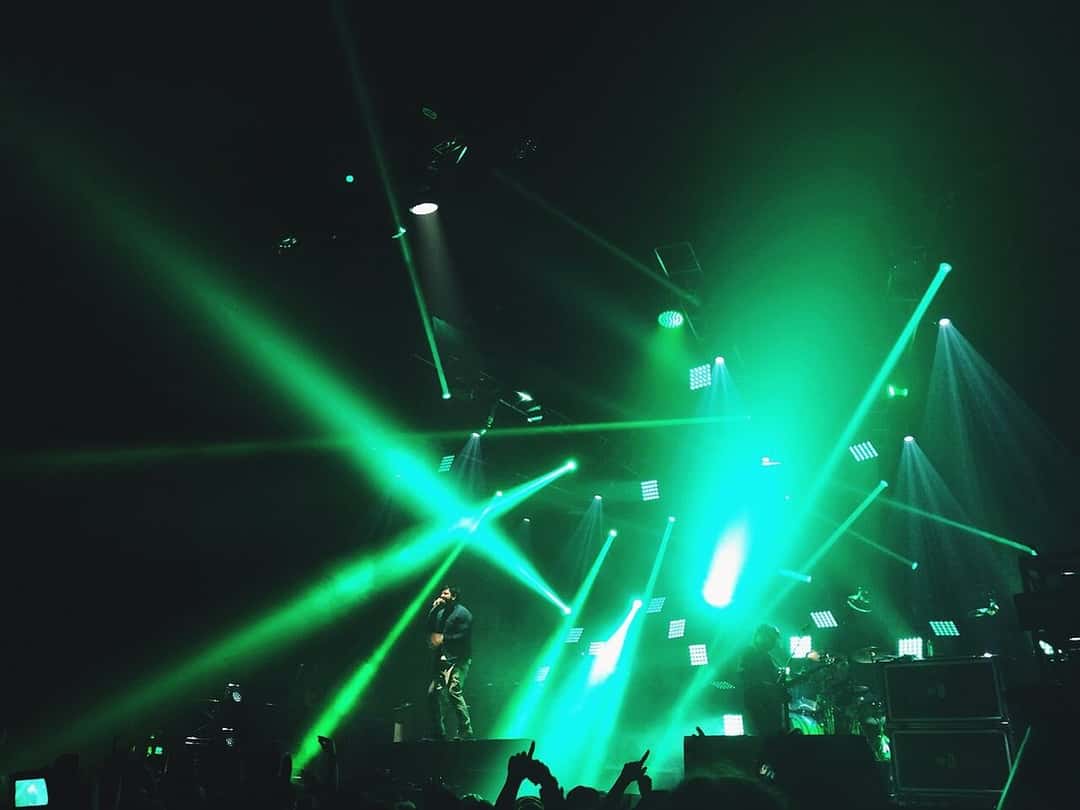 Deftones en vivo en un escenario oscuro atravesado por rayos de luz verde, con el público de espaldas en primer plano, en mayo de 2017 (foto de archivo). Foto: Sam Town, CC BY-SA 2.0, vía Wikimedia Commons