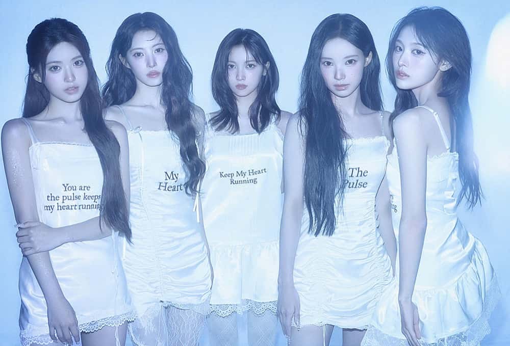 Foto conceptual oficial de RESCENE para «PULSE»: las cinco integrantes, de pelo largo y vestidos blancos con frases estampadas, posan juntas sobre un fondo celeste