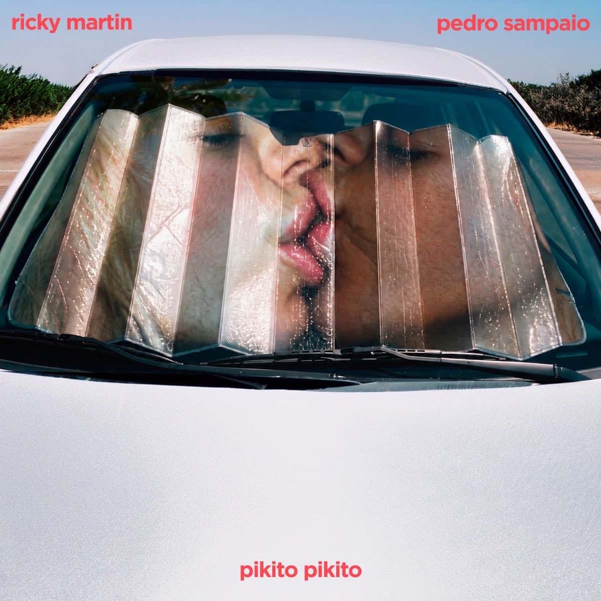 Portada de "Pikito Pikito": un auto blanco visto de frente con un parasol plateado en el parabrisas, a través del cual se ve a una pareja dándose un beso, con los nombres de Ricky Martin y Pedro Sampaio arriba en letras rojas y el título abajo