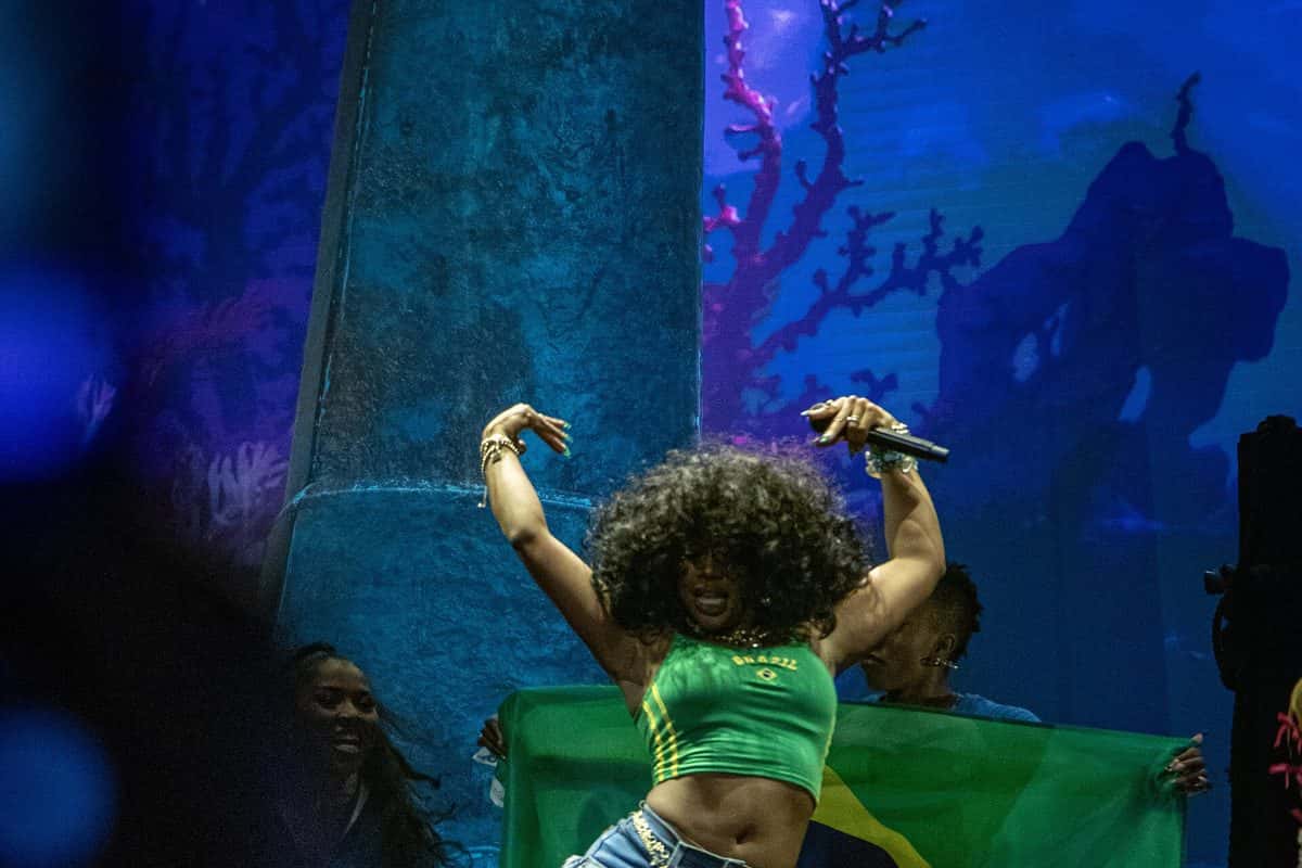 SZA baila en el escenario de Lollapalooza Brasil con un top verde que dice Brazil, mientras dos bailarinas sostienen una bandera brasileña detrás (foto de archivo, marzo de 2024)