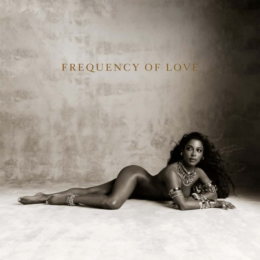 Portada oficial de Frequency of Love de Victoria Monét: la artista recostada sobre un piso claro, con joyas doradas y el título en letras ocres sobre un fondo sepia