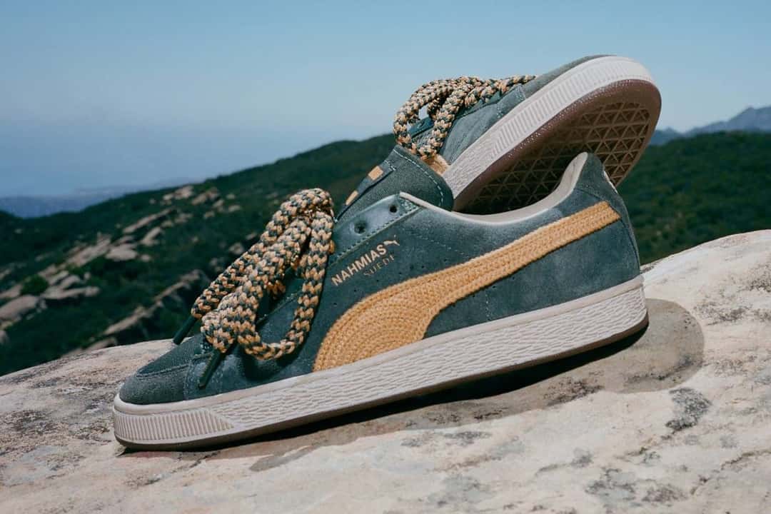 NAHMIAS x PUMA Suede Crochet verde de perfil sobre una roca, con la Formstrip tejida amarilla y los cordones gruesos de colores