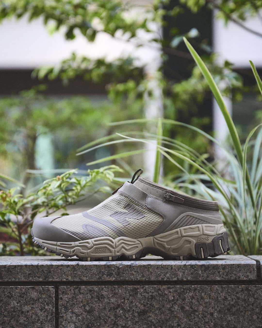New Balance Niobium Concept 1 en marrón claro sin la caña, convertida en mule con el talón abierto, sobre un muro de piedra