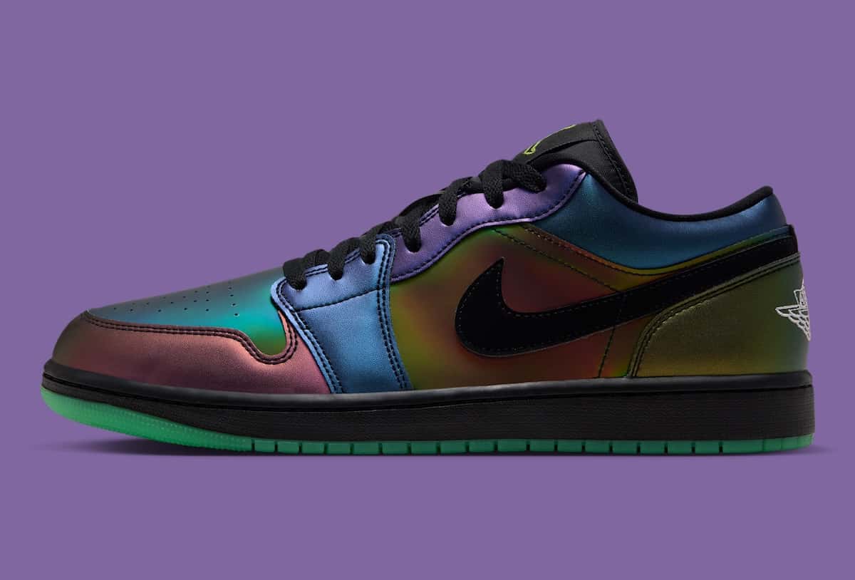 Air Jordan 1 Low SE de Space Jam de perfil sobre fondo violeta, con el upper iridiscente que pasa del verde al azul, violeta y cobre, Swoosh negro, cordones negros, Wings blanco en el talón y suela verde