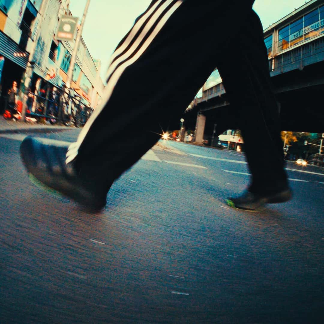 Campaña de Sneakersnstuff x adidas en la calle, con una persona caminando con la Adizero Evo SL Zip negra