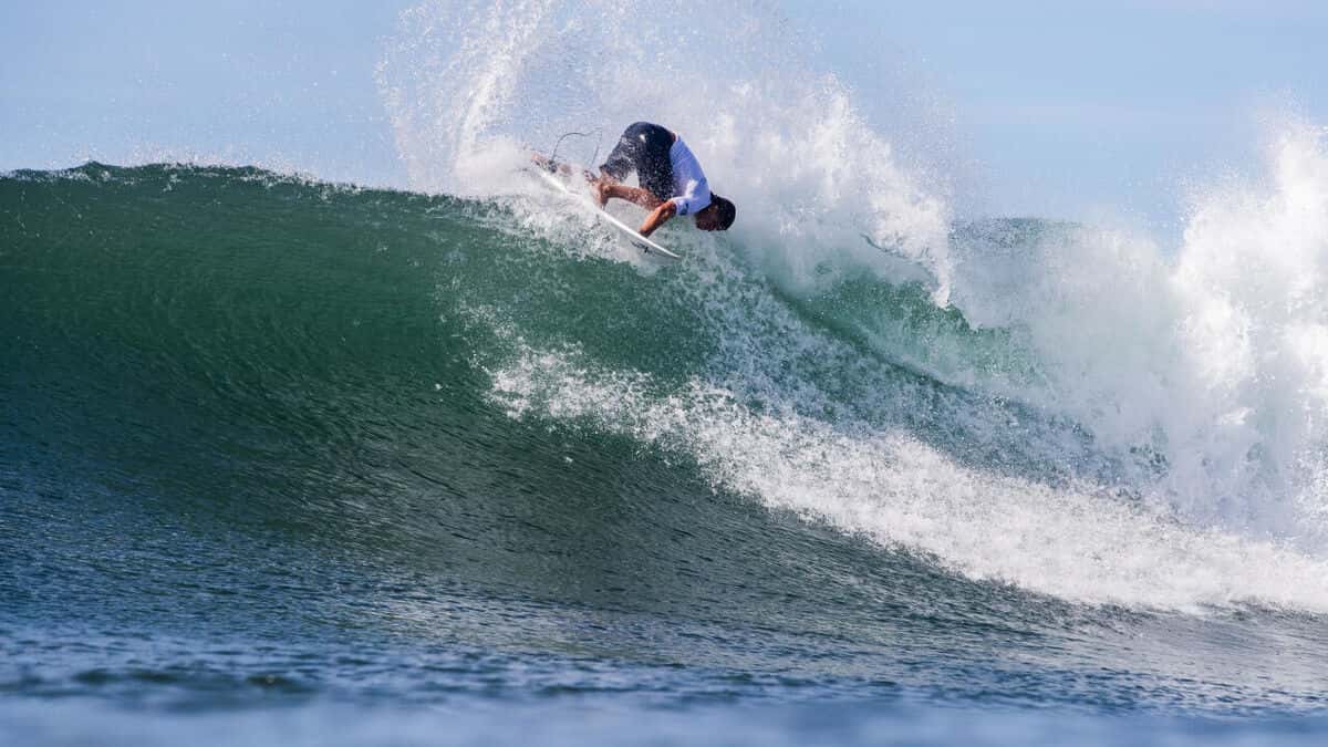 Koa Smith, con lycra blanca, tira un giro de revés en la cresta de una ola verde en Sunset Beach, durante el primer día del HTA Sunset Pro 2026