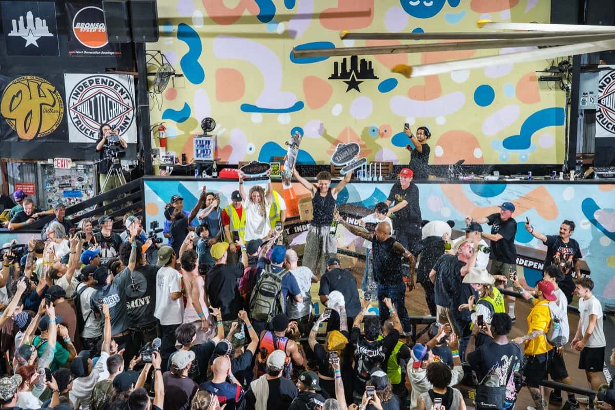 Festejo en la pista del Skatepark of Tampa el día de la final del Tampa Am 2026: un skater levanta los brazos con tablas en alto, rodeado de público