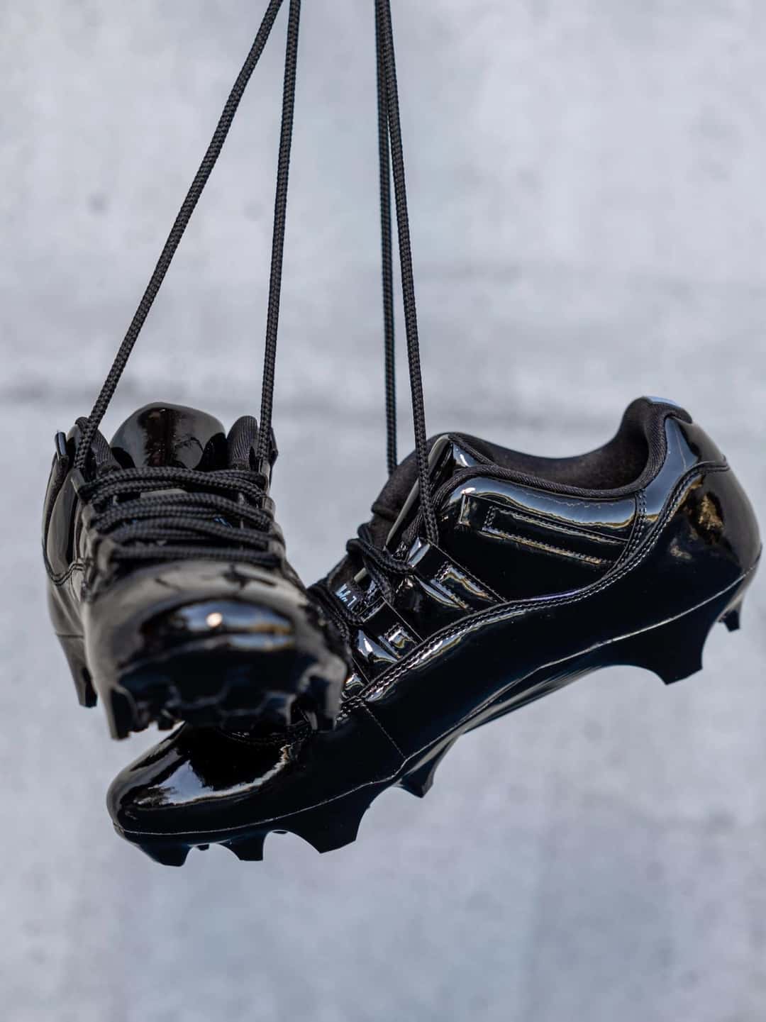 Botines Air Jordan 11 Gammas de UCLA en charol negro colgados de los cordones, con los tapones a la vista